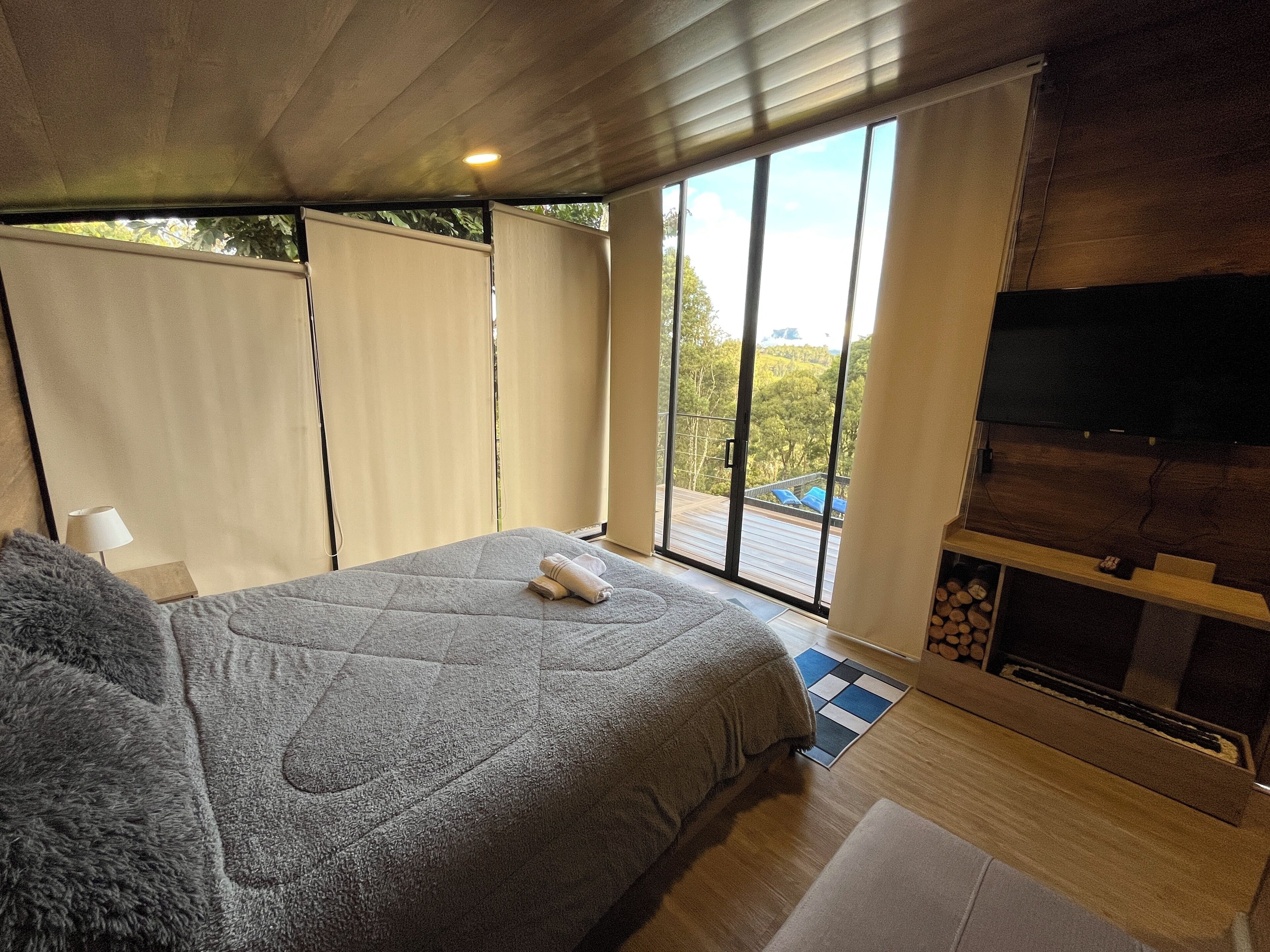 Ein Schlafzimmer mit einem großen Bett, einem Fernseher und Blick ins Freie.