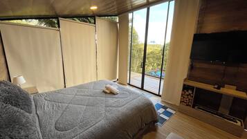 Ein Schlafzimmer mit einem großen Bett, einem Fernseher und Blick ins Freie.