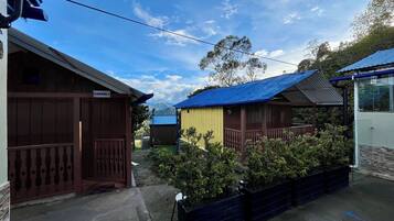 A row of cabins with wooden exteriors and blue roofs, surrounded by greenery.