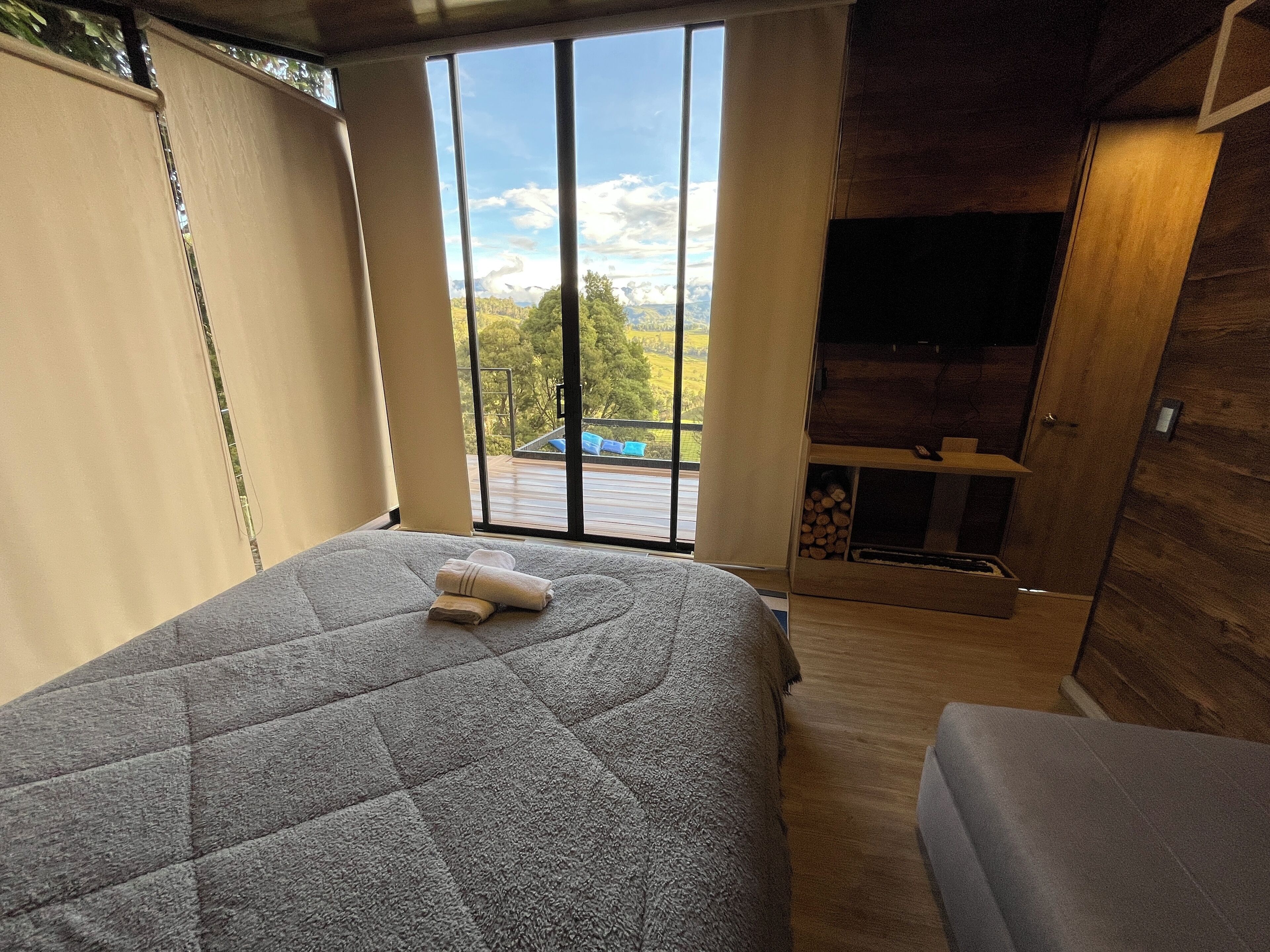 Une chambre dotée d’un grand lit, d’une télévision et offrant une vue sur une piscine et des montagnes, grâce à une porte-fenêtre coulissante.