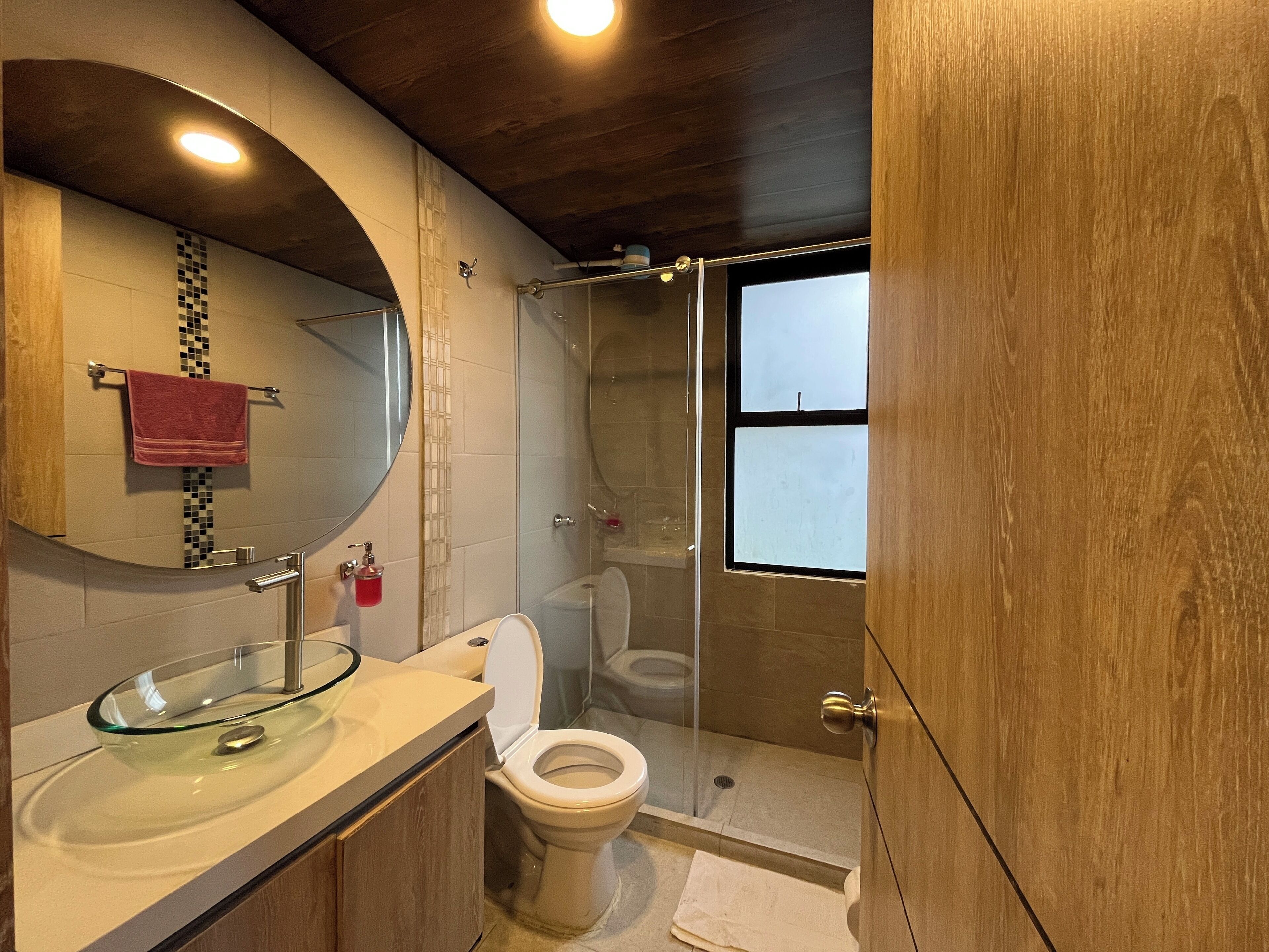 A bathroom with a glass sink, a toilet, and a shower enclosure.