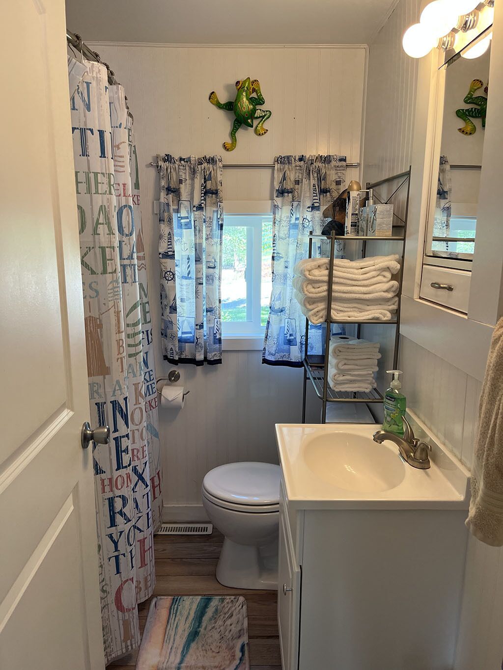 A bathroom with a toilet, sink, and shower curtain with nautical designs.