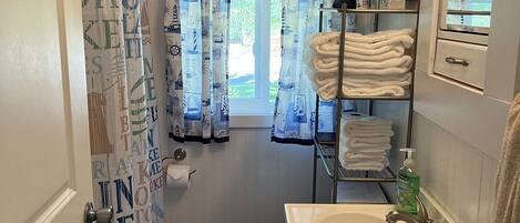 A bathroom with a toilet, sink, and shower curtain with nautical designs.