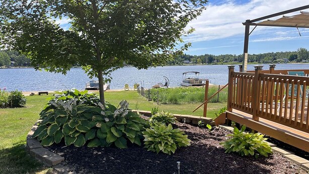 Une terrasse au bord du lac, dotée d’une rambarde en bois, d’un chemin pavé de pierres et d’une variété de plantes.