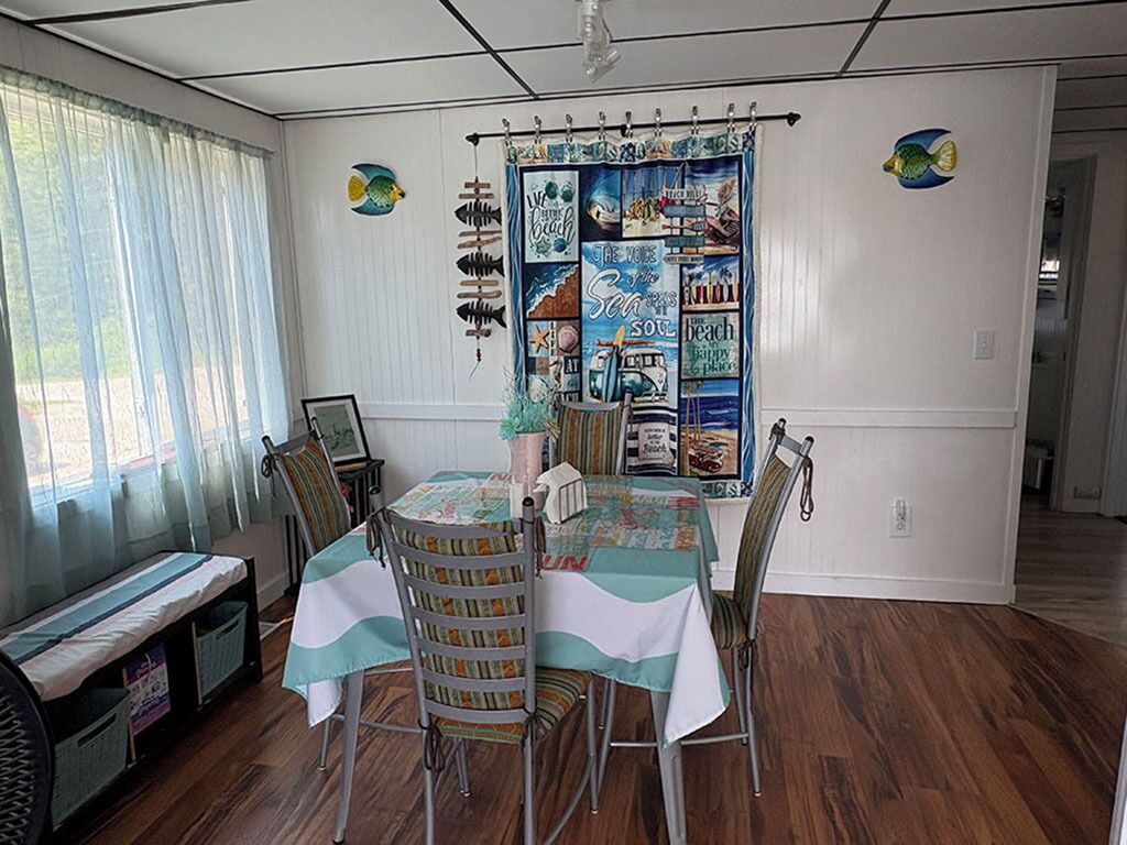 A dining area with a table and chairs, a bench, and a wall with a nautical-themed tapestry.