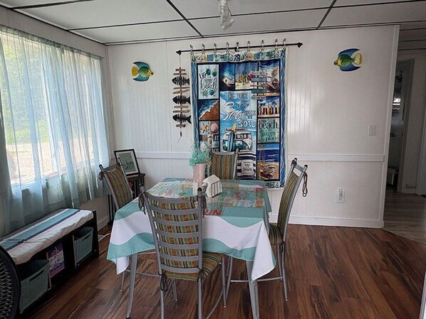 A dining area with a table and chairs, a bench, and a wall with a nautical-themed tapestry.