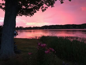 A lakeside view with a dock, trees, and a pink sky. - Cozy Lakefront Cottage Getaway in Kent County, Michigan (Rockford)