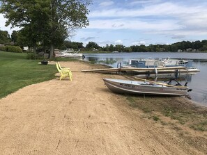 A sandy beach with a yellow chair and a rowboat named 'Sea Nymph' docked at the water's edge.