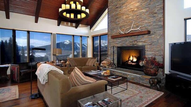 A living room with a fireplace, large windows, and a television. - Elk Run-Hot Tub, Pet Friendly, and Close to Slopes (Mt Crested Butte)