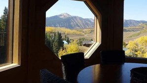 A room with a large octagonal window offering a view of mountains and autumn foliage. - Elk Run-Hot Tub, Pet Friendly, and Close to Slopes (Mt Crested Butte)