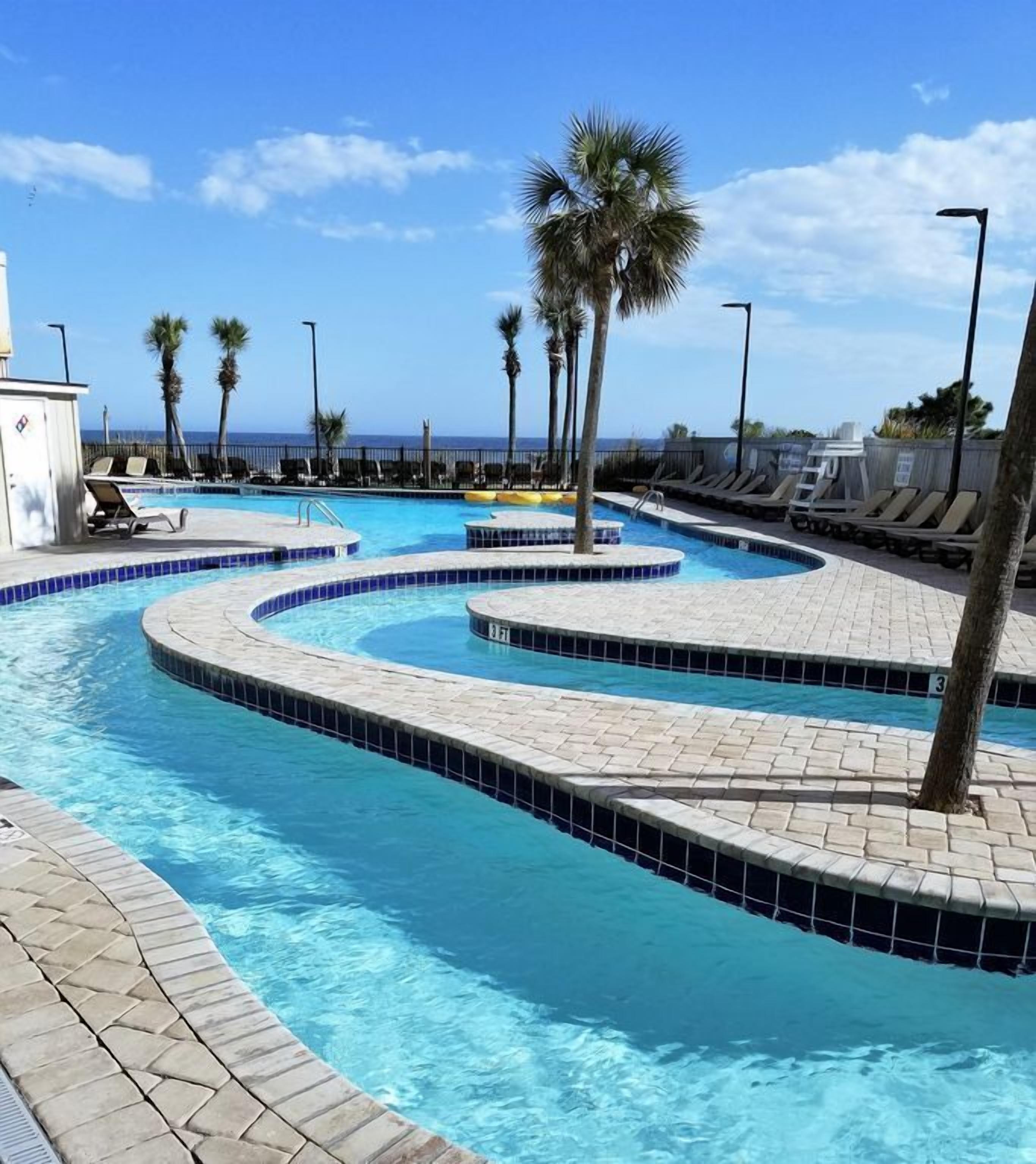 A swimming pool with multiple lanes, palm trees, and lounge chairs.