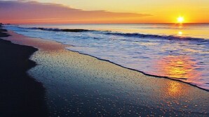 Una playa al atardecer con olas acariciando suavemente la orilla.