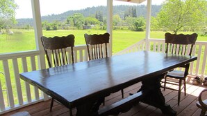 A wooden deck with a table and chairs, overlooking a green landscape.