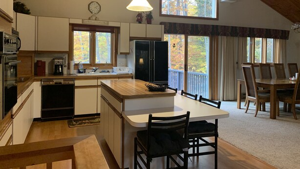 A spacious kitchen with wooden cabinets, a central island, and a dining area with a large table and chairs.