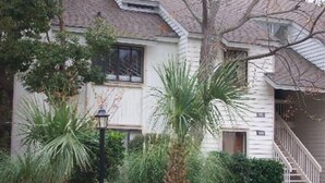 Une maison à deux étages avec un porche à l’avant, un escalier et une boîte aux lettres.