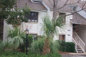 Een twee verdiepingen tellend huis met een veranda, een trap en een brievenbus.