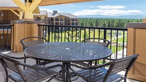 Relax in a serene outdoor space with a round table and four chairs, surrounded by a forested landscape.