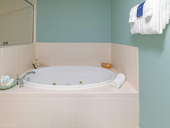 A bathroom with a freestanding bathtub, a small decorative statue, a wicker basket, and a towel rack with a folded towel.