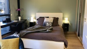 Une chambre à coucher avec un lit, des tables de chevet, un bureau et une chaise.