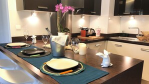 Une cuisine moderne dotée d’un îlot central, d’appareils électroménagers en acier inoxydable et d’une composition florale décorative avec des orchidées.