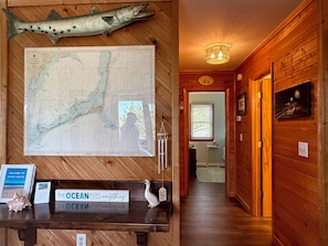 A wooden interior with a map, a sign reading 'The Ocean Fixes Everything,' and a large fish mounted on the wall.
