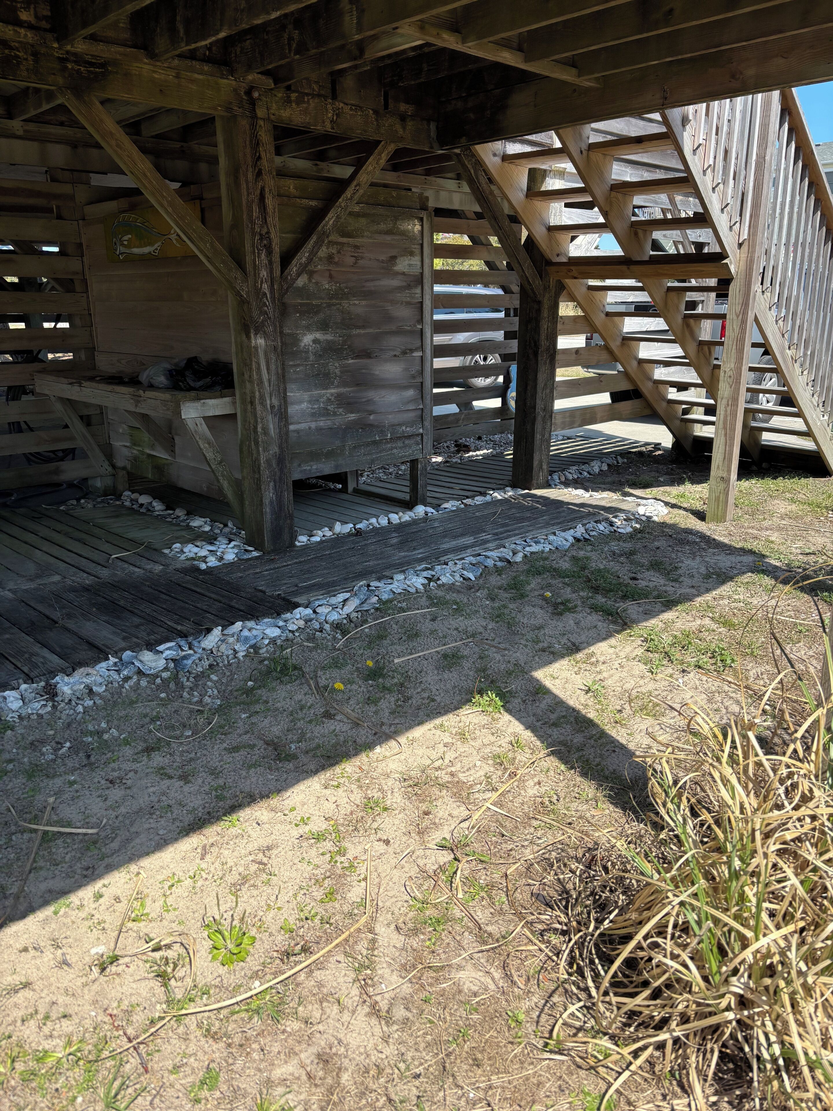 A wooden structure with a sloped roof, gravel flooring, and a wooden staircase.