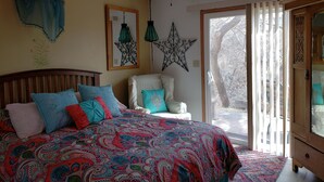 Ein Schlafzimmer mit einem großen Bett, einem Deckenventilator und Blick ins Freie durch eine Schiebetür.