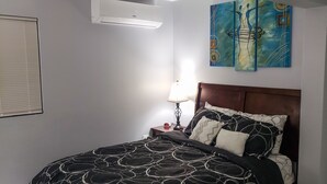 A neatly made bed with a patterned bedspread, a bedside lamp, and a wall-mounted air conditioner. - Home away from home ... secure and serene location with all the comforts of home (Christiansted)
