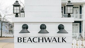 A white sign with the name 'BEACHWALK' and three black lantern-style lights above it.