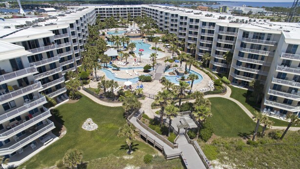 Un hôtel de grande hauteur doté de nombreux balcons, d’une piscine centrale et entouré de verdure.