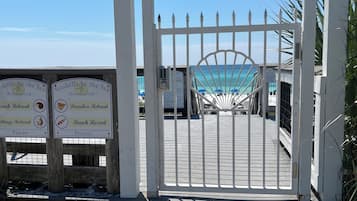 A gated entrance with a 'NO TRESPASSING' sign, a wooden walkway, and signs for private beach retreats.