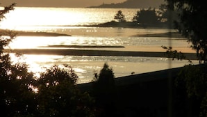 A sunset view over a calm body of water with a distant shoreline and trees. - Potters View Guesthouse, Parksville (Parksville)