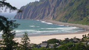 A coastal view with a beach, cliffs, and houses. - Family Favorite! Treehouse,Huge Yard,Firepit & EV Charger.Walk to town & beach (Nehalem)