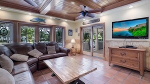 A spacious living area with a leather sofa, wooden coffee table, and a television on a wooden cabinet.