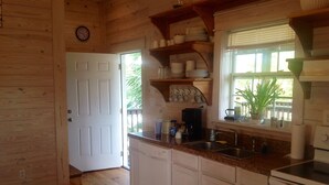A wooden-paneled kitchen with white cabinets, a coffee maker, and a window with blinds. -  The Beach House on Florida's Forgotten Coast (St. Joe)