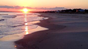 Une plage au coucher du soleil, avec le soleil qui se reflète sur l’eau.