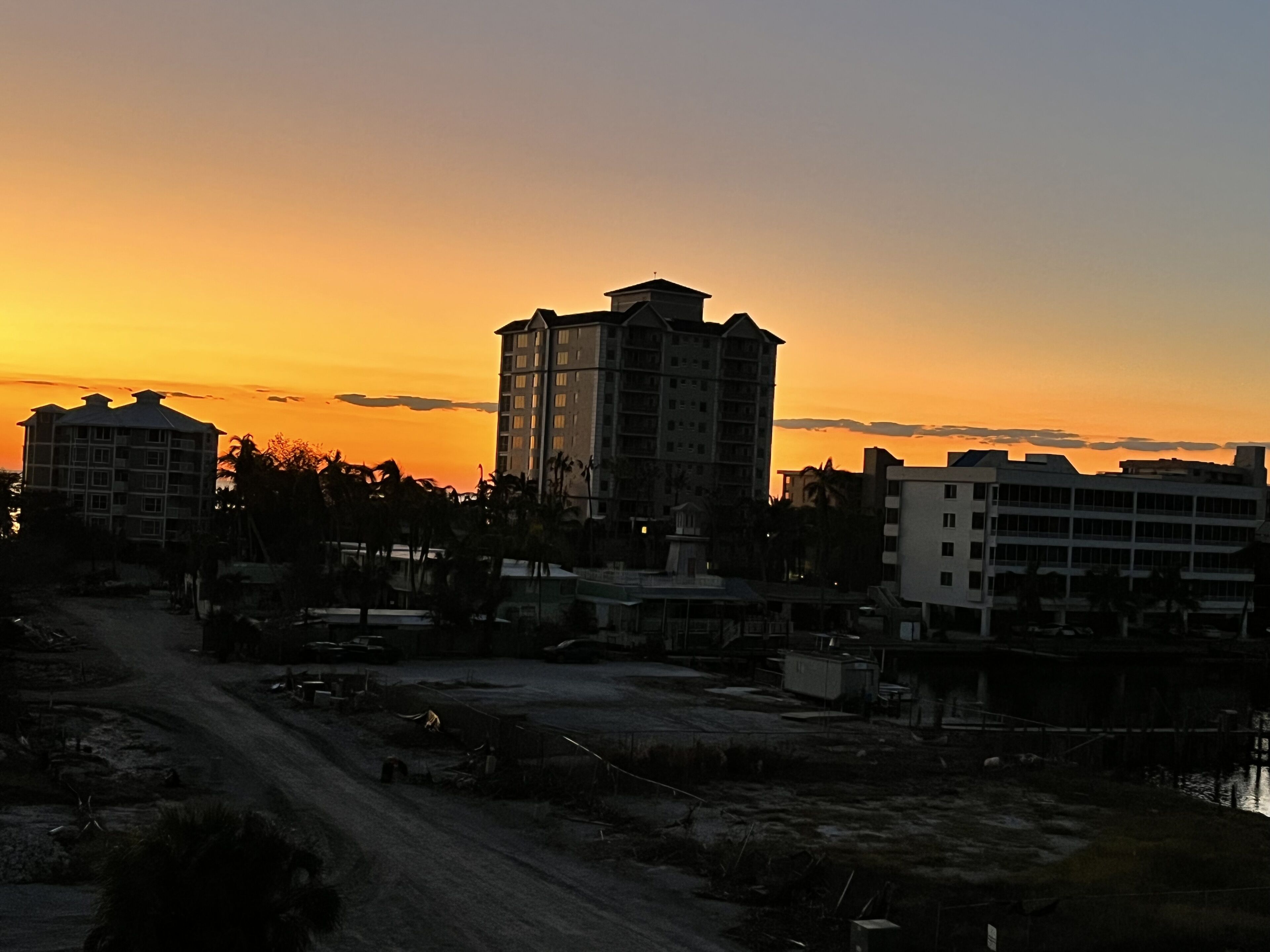 A cityscape at sunset with buildings silhouetted against the sky.