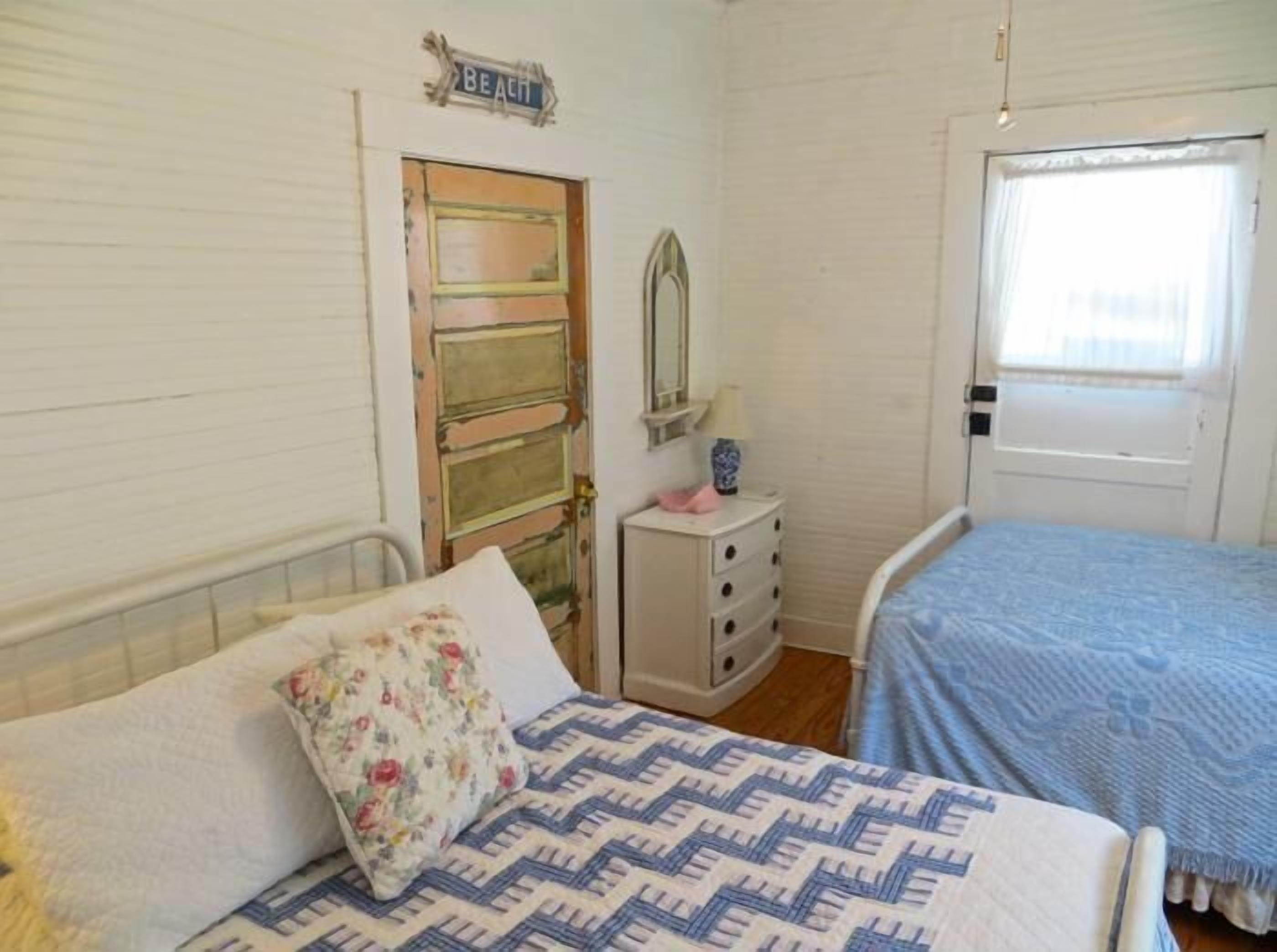 A bedroom with a bed, a dresser, a mirror, and a door.