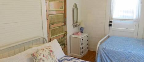 A bedroom with a bed, a dresser, a mirror, and a door.