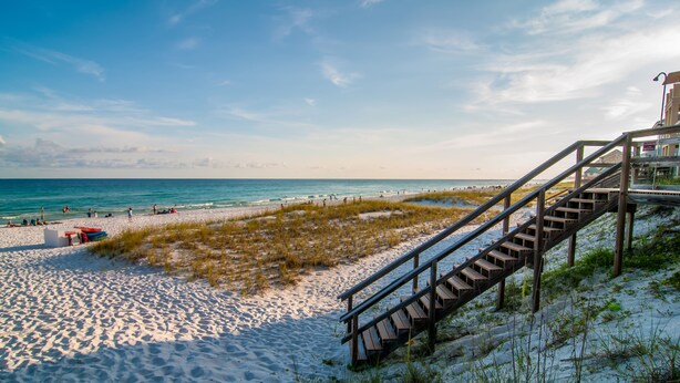 A beach with a wooden staircase leading to a building.