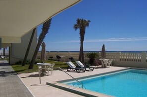 Relax by the ocean with a clear view, surrounded by lounge chairs and umbrellas.