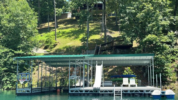A docked boat with a covered seating area and a basketball hoop.