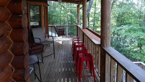 A wooden deck with a railing, a chair, and a table.