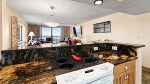 Una cocina moderna con encimera de granito, estufa blanca y comedor con vistas.