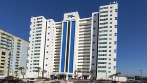 Un hotel de varios pisos con una fachada destacada en azul y blanco, que presenta una banda vertical azul en el centro y el logotipo 'RTP' en la parte superior.