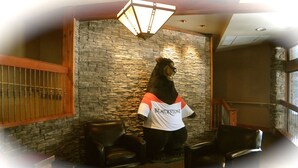 A bear statue wearing a Blackstone t-shirt, stone walls, and leather chairs in a lobby area. - Enjoy Mountain Views @ Fully Equipped 2BR2BA Hotel Condo (Canmore)