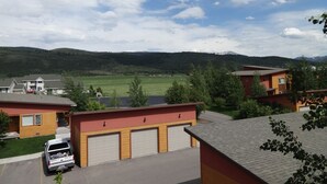 A residential area with houses, a parking lot, and a view of a green field and mountains in the distance.