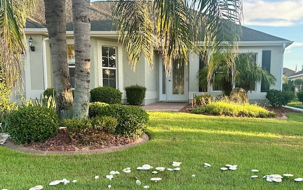 A residential house with a well-maintained lawn, a front porch, and a driveway.
