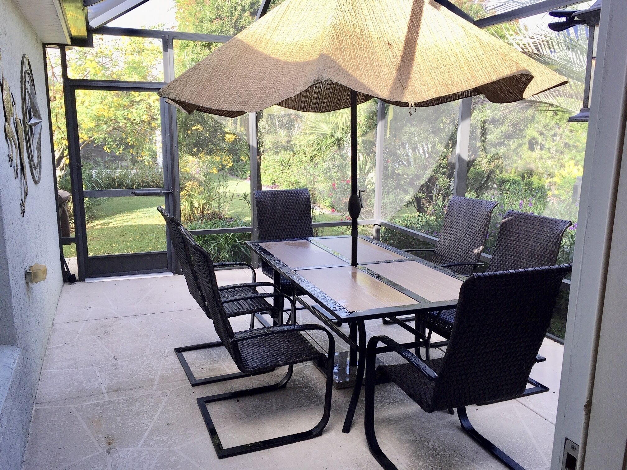 Une terrasse couverte avec une table et des chaises, de grandes fenêtres et une vue sur le jardin.