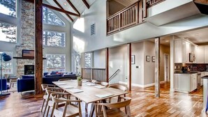 Un amplio salón con una gran mesa de comedor de madera, asientos cómodos y vistas al exterior.